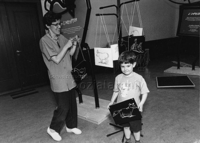 Messe oder Ausstellung, wahrscheinlich in der Westschweiz - Frau und Kind mit umgehängtem Schild; um 1995