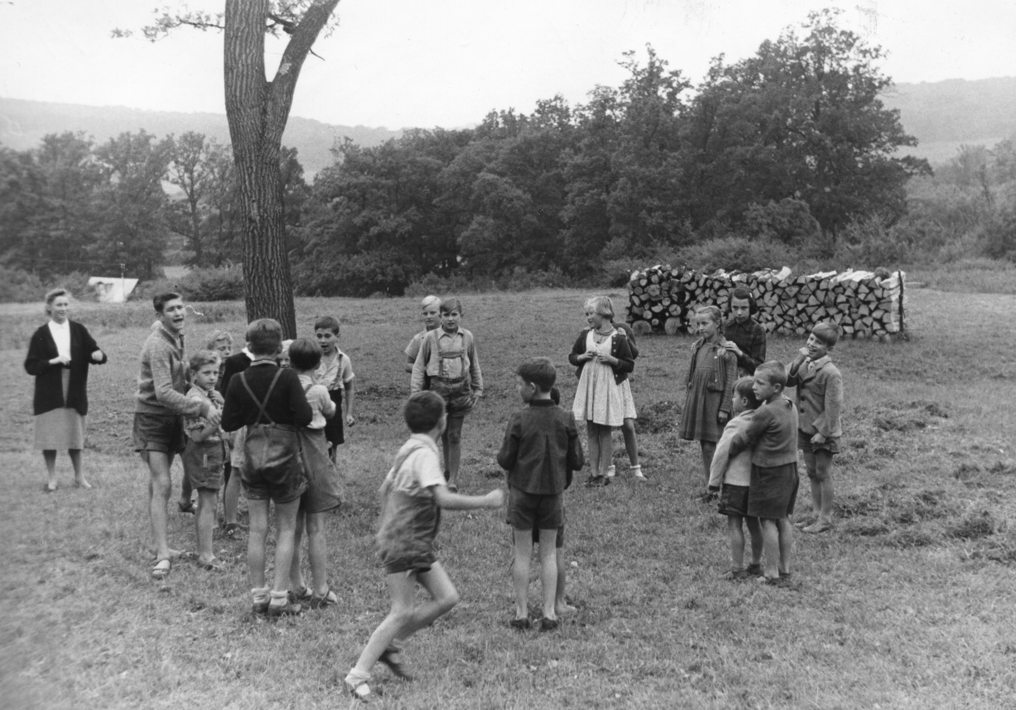 "Not u. Hilfe 53; Sommer 1953 - Hörndlwald: Ferien für Flüchtlingskinder mit Hilfe des Schweizerischen Arbeiterhilfswerkes und der Schweizer Europahilfe; Volkshilfe Wien." Eine Gruppe von Kindern spielen auf einer Wiese