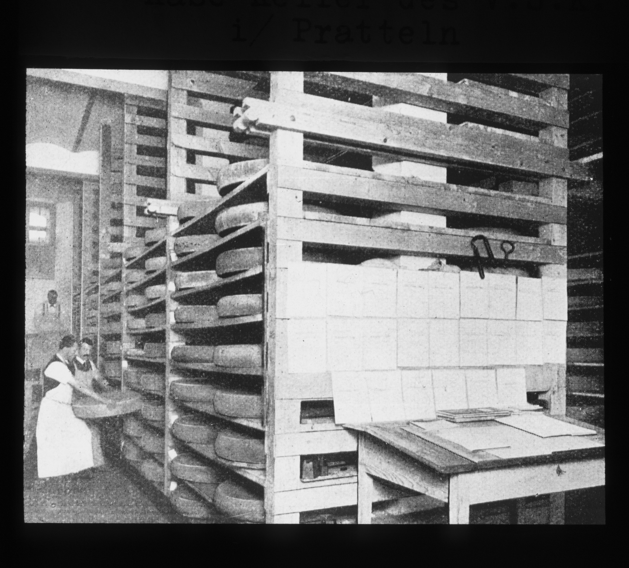 Dia: Zwei Käser wuchten einen grossen Laib in ein Regal im Käsekeller des V.S.K. (Verband schweizerischer Konsumvereine) in Pratteln.