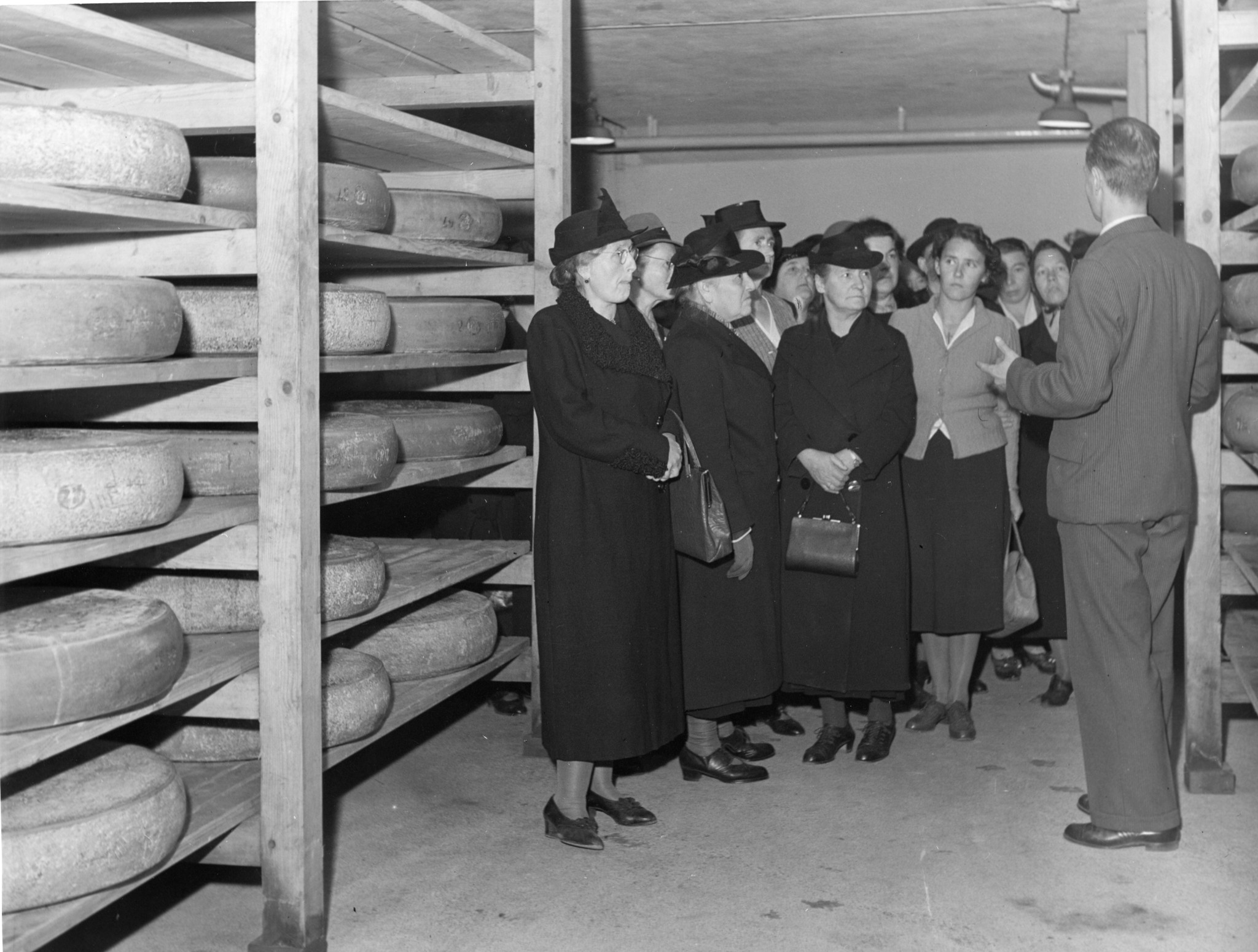 Frauen auf Betriebsbesichtigung in einem Lagerraum für Käse des Lebensmittelvereins Zürich