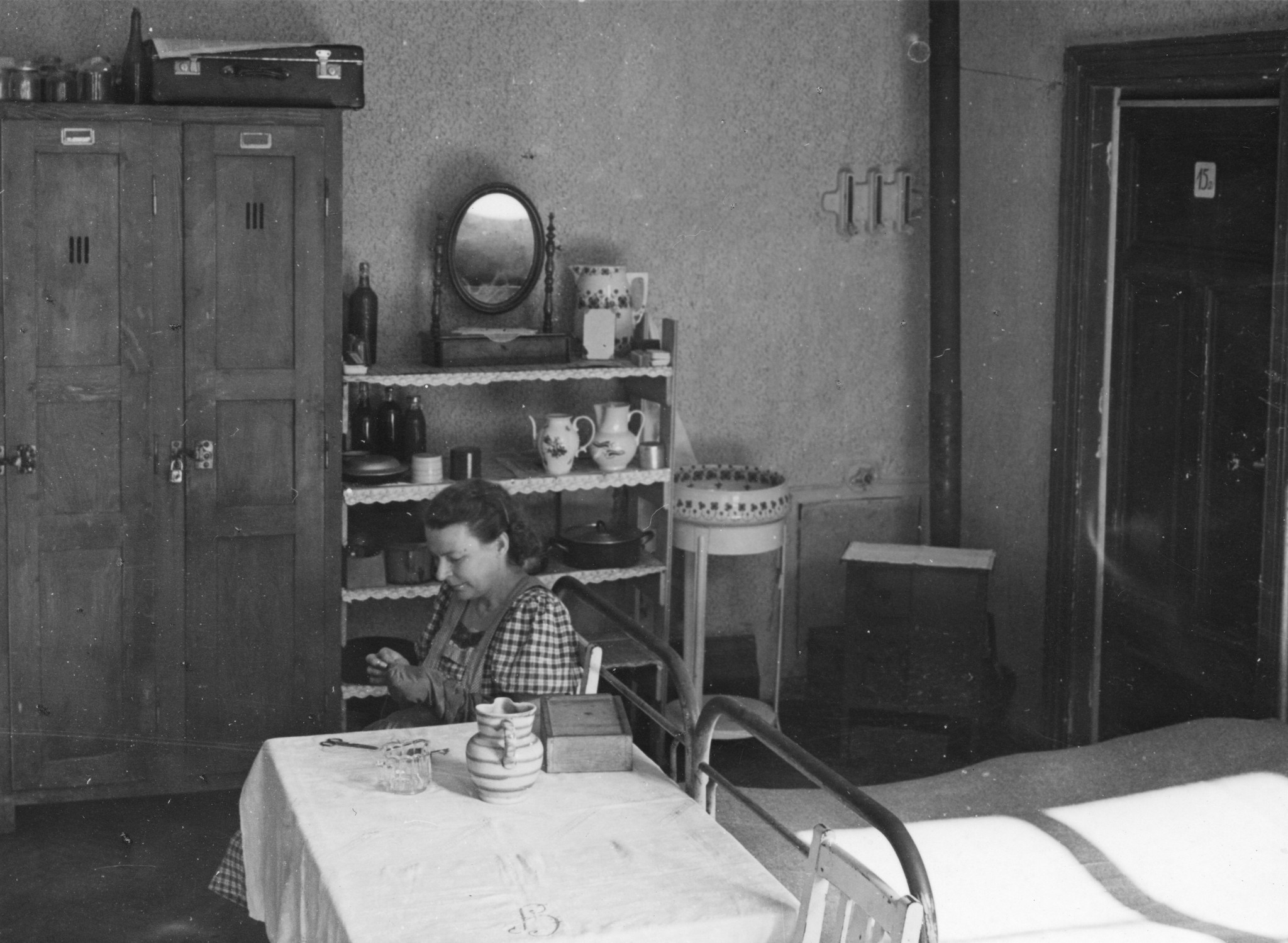 "Okt. 1949, Flüchtlingslager am Hundsturm, Gemeinschaftsküche", Frau bei Näharbeit