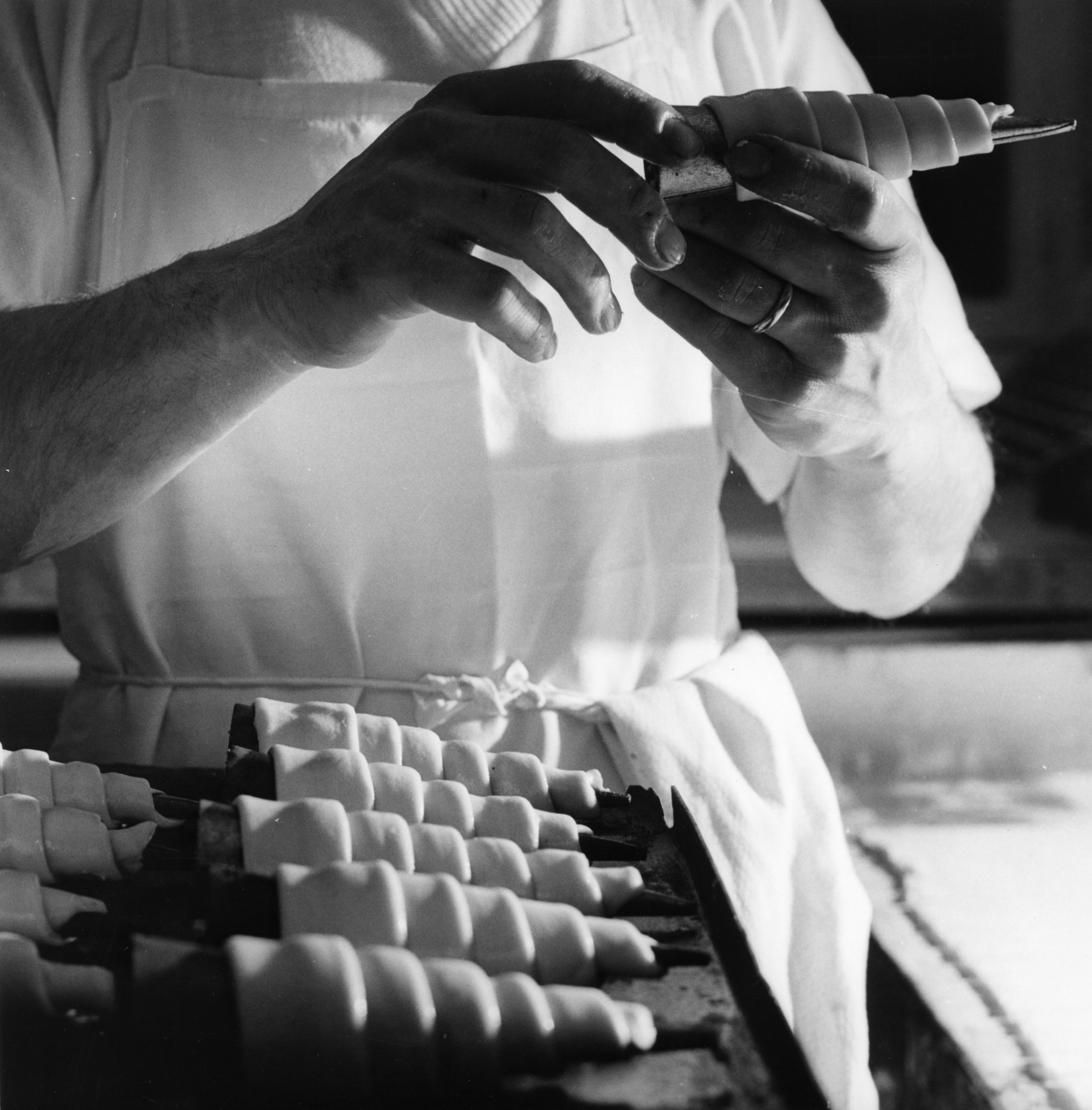 Mann bei der Arbeit (Herstellung von Crème-Cornets?)