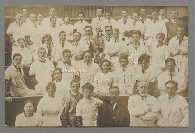 Gruppenporträt von Studentinnen und Studenten in weissen Kitteln und Lehrbeauftragten der Medizin, Skelett mit Tabakpfeife, um 1918, Poststempel: 1918