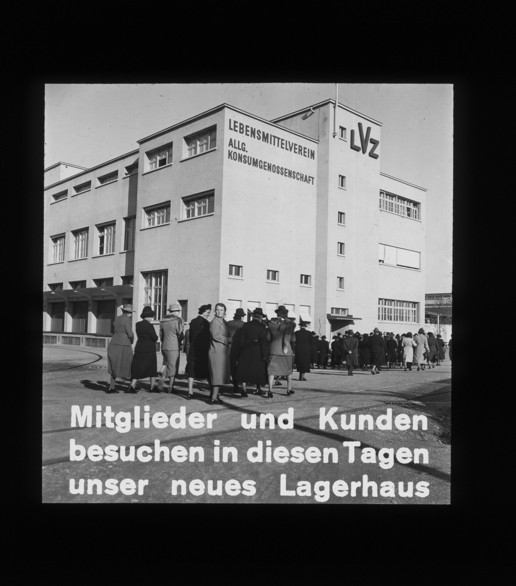 Dia: Lagerhaus von aussen, davor viele Menschen: "Mitglieder und Kunden besuchen in diesen Tagen unser neues Lagerhaus".