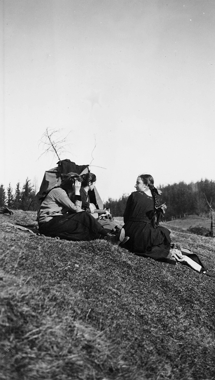 Mädchen der Wandervogelortsgruppe St. Gallen-Klösterli sitzen auf der Wiese, ein Mädchen Gitarre spielend (1920)