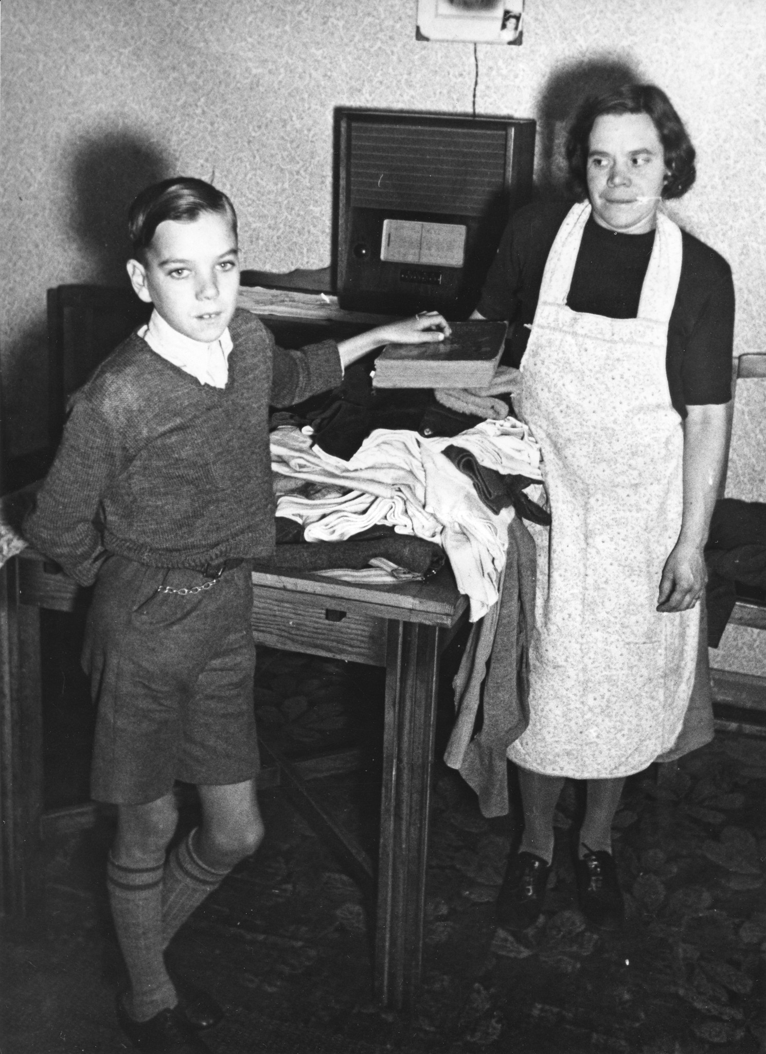 "Aktion Swiss Mountain Cure Aid for British Children. London, vor der Abreise in die Schweiz". Eine Mutter packt ihrem Sohn den Reisekoffer