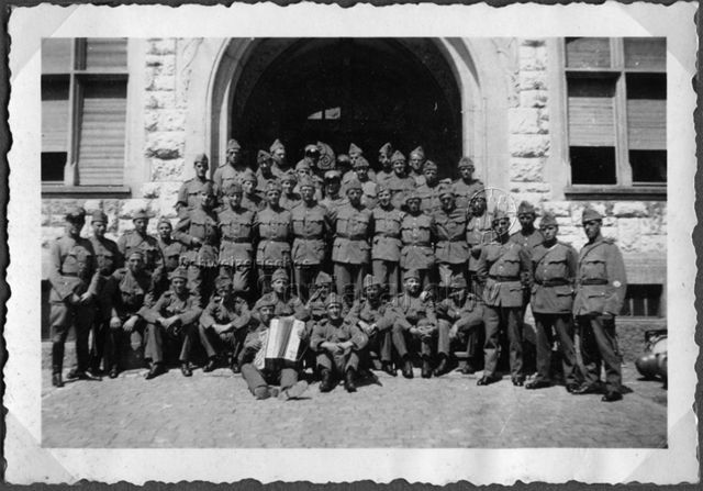 Album Alfred Brauchli, Teil 1/3: 699 Tage Aktivdienst 1939-1945 als Sanitätssoldat bei der Sanitätskompanie I/​7, Thurgau: Gruppenfoto vor Hauseingang mit Soldaten in Uniform, einer spielt Handorgel