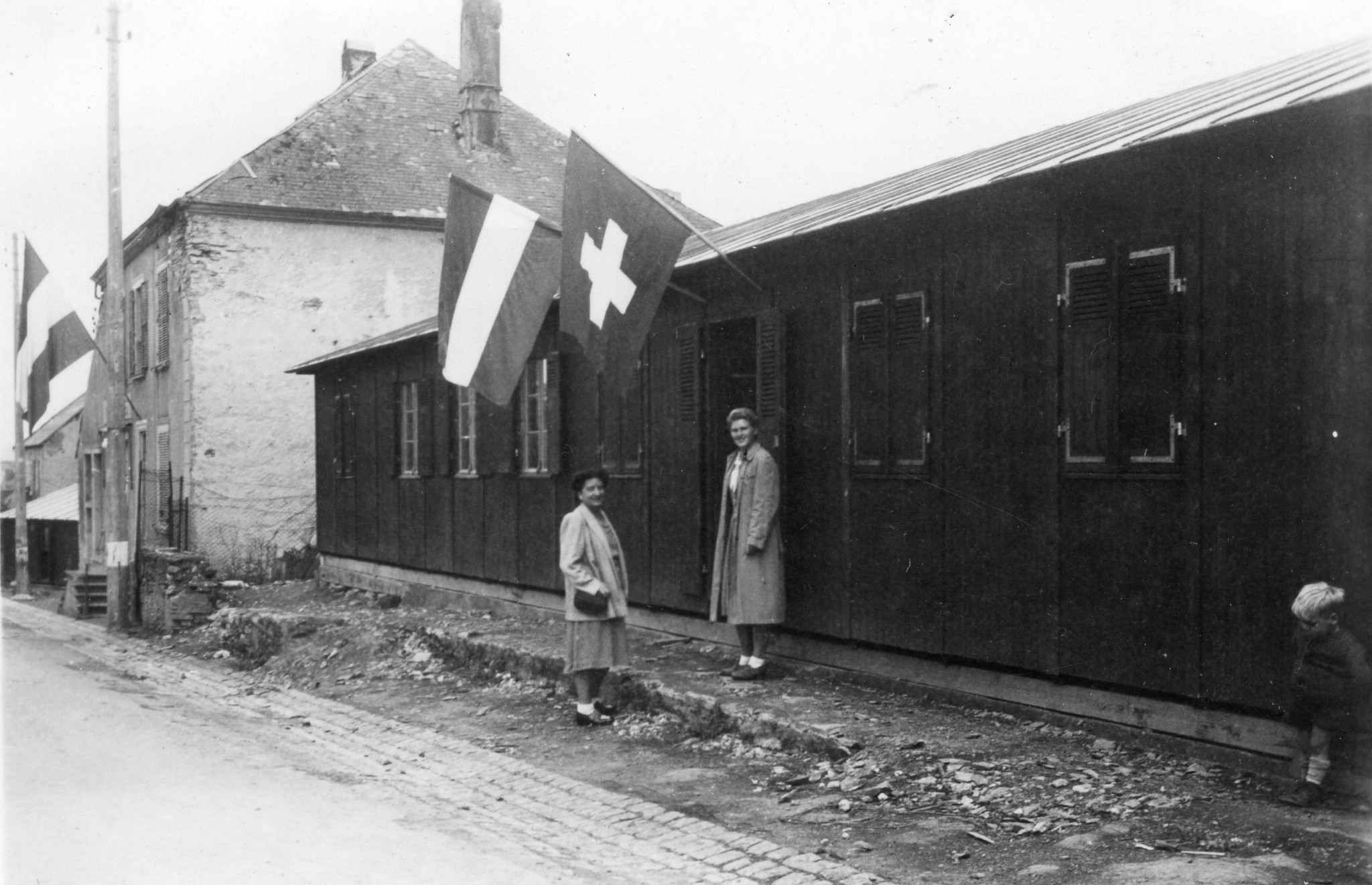 Zwei Frauen stehen vor einem Haus mit Schweizer Flagge