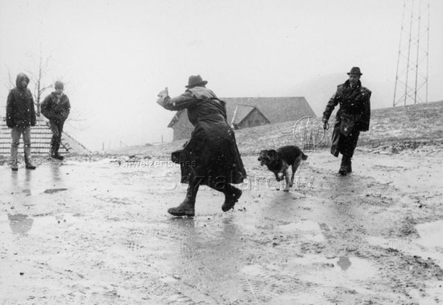 Zwei Jungen schauen zwei Männern mit Hund zu; um 1970