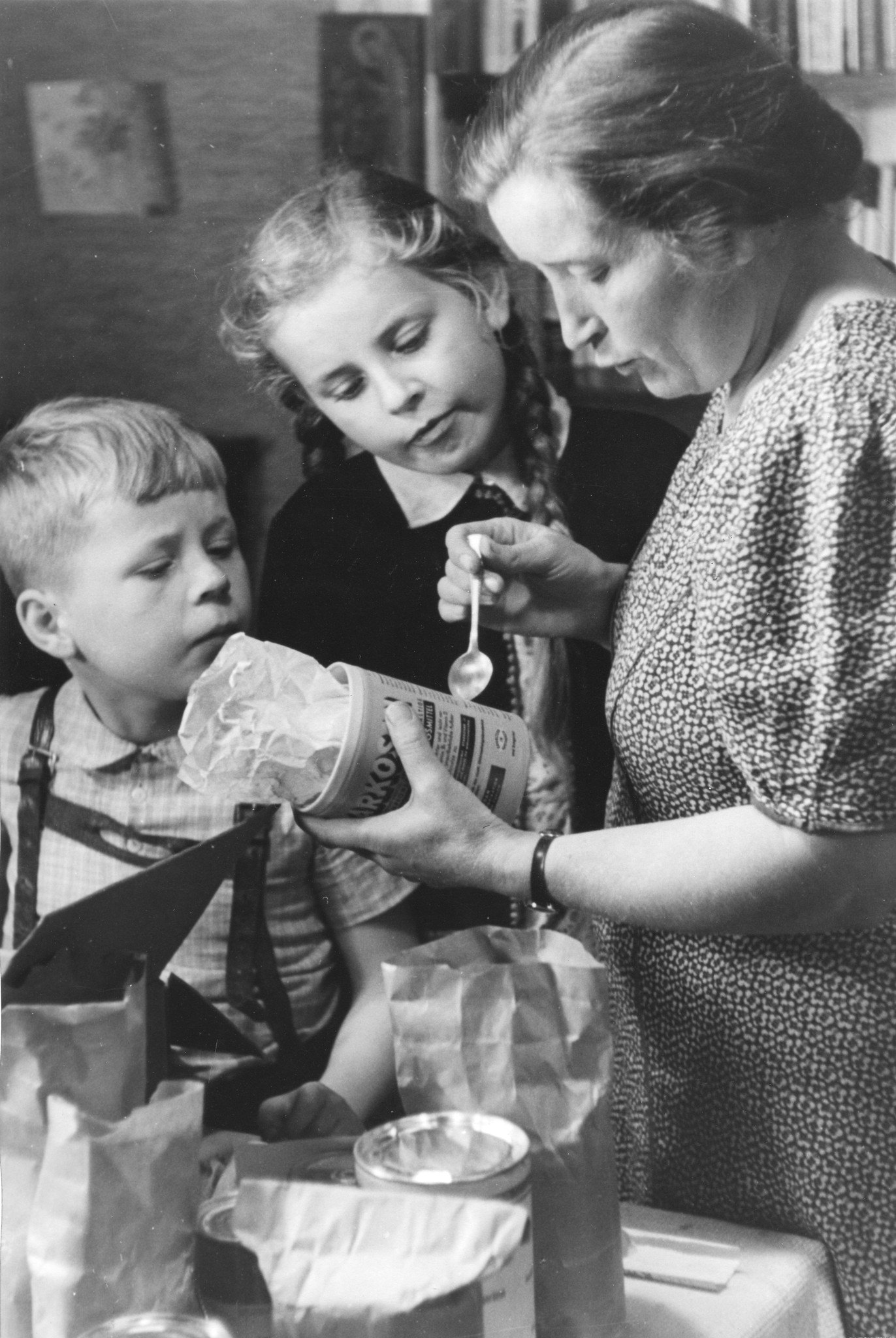 "Hamburg, Sommer 1948: ein Freipaket kommt an!"; eine Mutter liest den Kindern den Aufdruck auf der Büchse vor