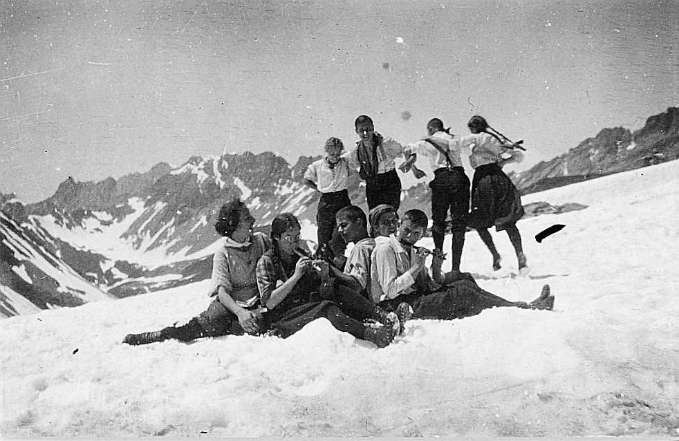 Zürcher Wandervögel in den verschneiten Bergen (Engadin) - Zwei Wandervögel spielen Block- und Querflöte, vier Wandervögel tanzen au