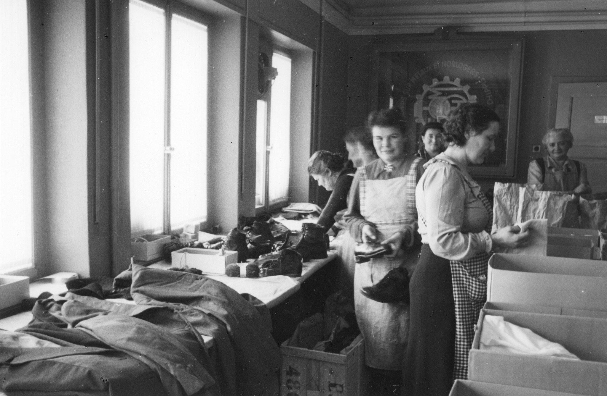 Sammellager im Haus des SMUV Sierre- Aktion zugunsten notleidender Gewerkschafter; Frauen Schuhe und Kleider in Kartonschachteln einpackend