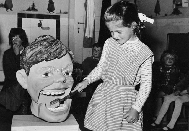 Zahnhygiene, Schulzahnarzt - Ein Mädchen putzt die Zähne eines Modellkopfes; um 1960
