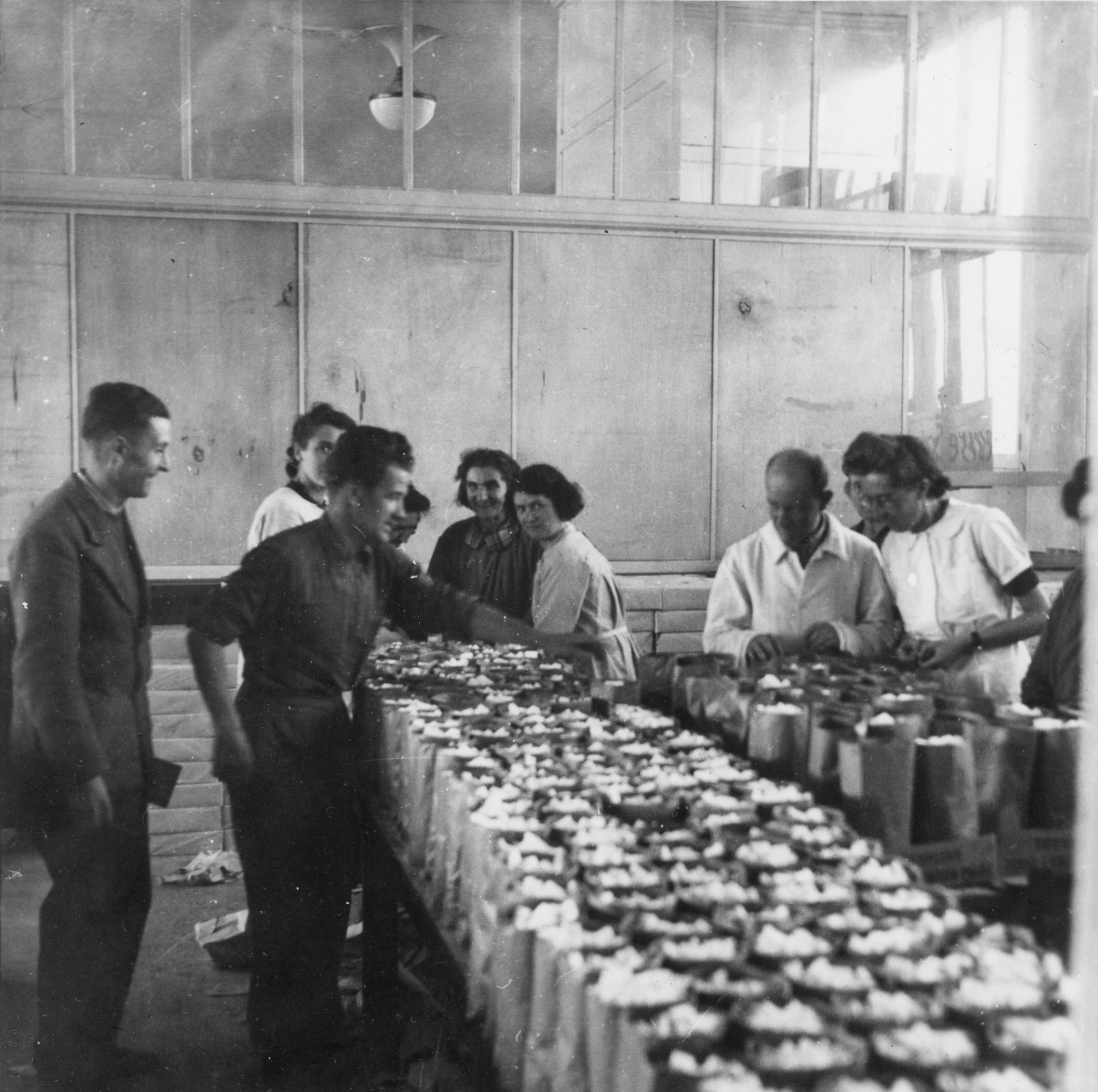 "Lyon, Oktober 1944. Seit Montag morgen werden Tüten gemacht, und die Füllung der Tüten vorbereitet." Helfer beim Vorbereiten von Rationen mit Zuckerwürfeln