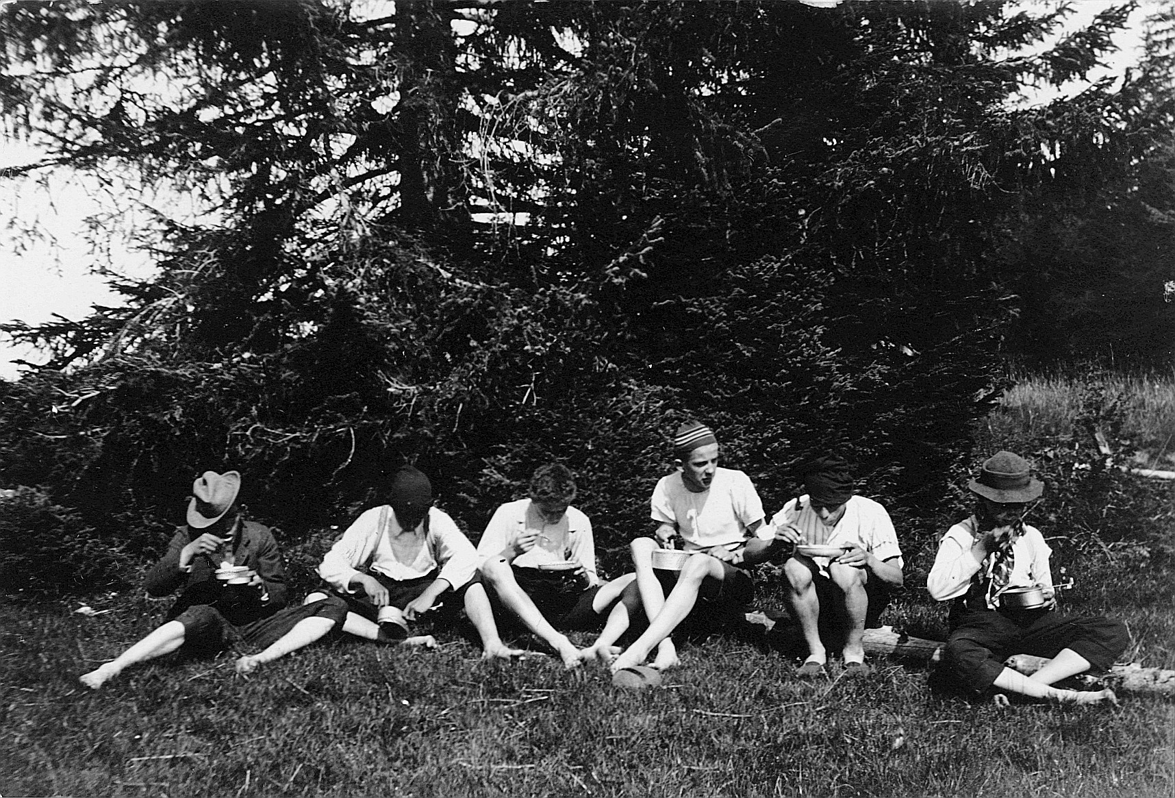 Wandervögel sitzen auf der Wiese und essen aus ihren Essnäpfen (1912)