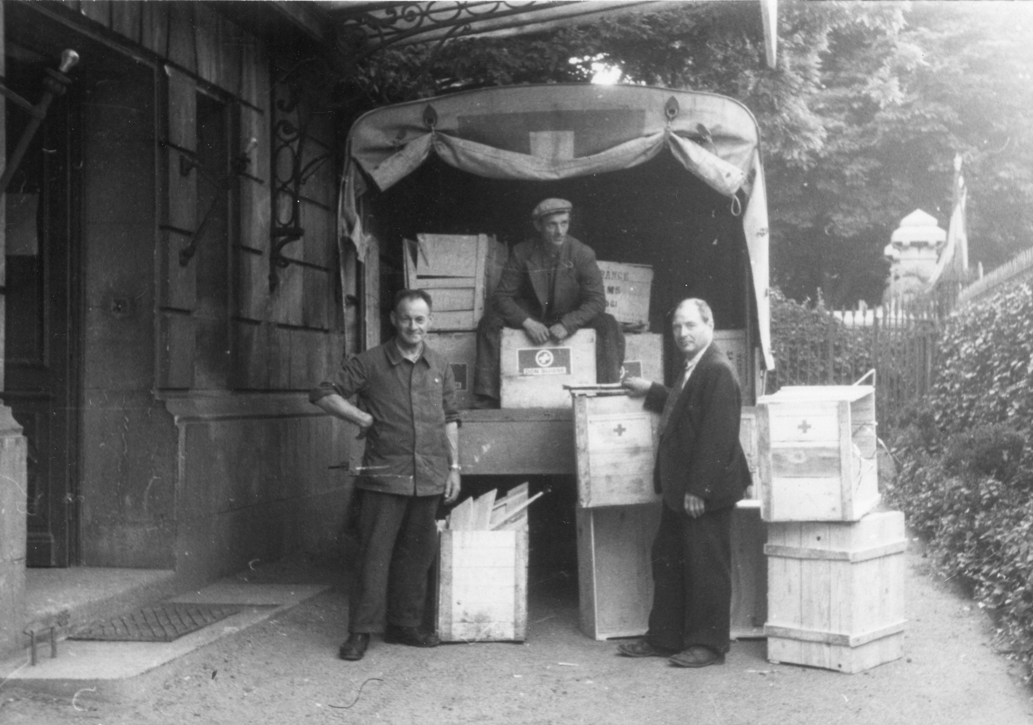 "Saint-Etienne, 1945. Unsere Waren kommen an." Männer beim Abladen eines Lastkraftwagens, Kisten "Don suisse"