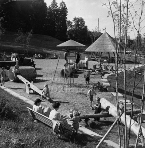 "Siedlungsspielplatz Sonnengarten, Zürich" - spielende Kinder in der Anlage, Betonröhren, ausrangiertes Fahrzeug, Klettergerüst, Wippe; um 1960