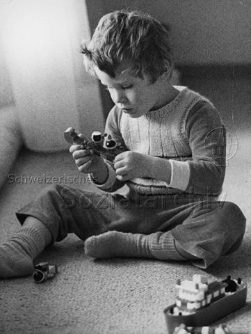 "Freizeitbeschäftigung innen" - Junge sitzt auf dem Fussboden und spielt mit Lego; um 1965