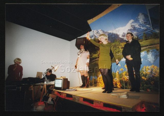 Performance, Gruppe GMAM (München/Berlin), auf Podest vor Tapete mit Alpenpanorama