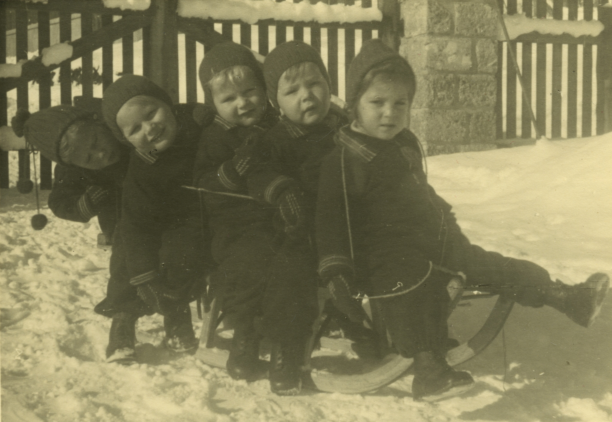 "Schwyzerhüsli"; fünf Kleinkinder auf einem Schlitten im Schnee sitzend