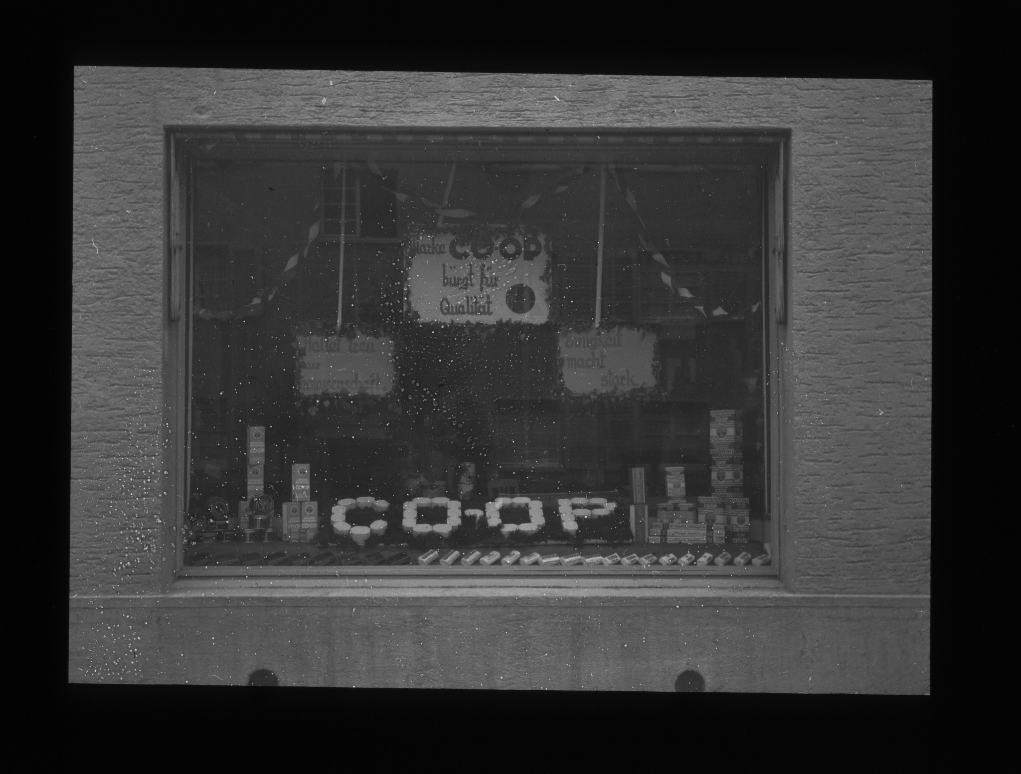 Dia: COOP/LVZ-Filiale: Schaufenster mit Text: "COOP bürgt für Qualität" und "Haltet treu zur Genossenschaft" und "Einigkeit macht stark".