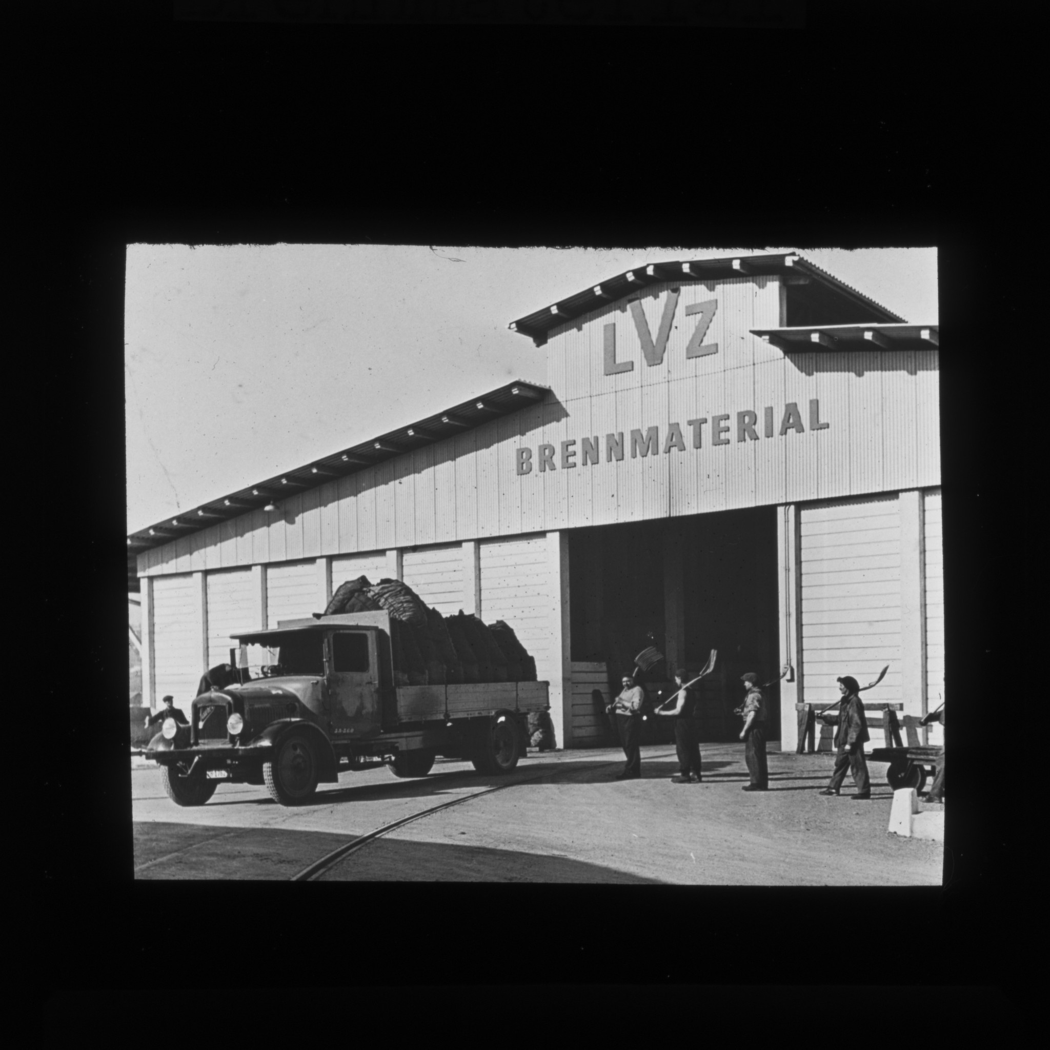 Dia: Lager des LVZ an der Turbinenstrasse: Brennmaterial. Davor beladene Lastwagen und Arbeiter.