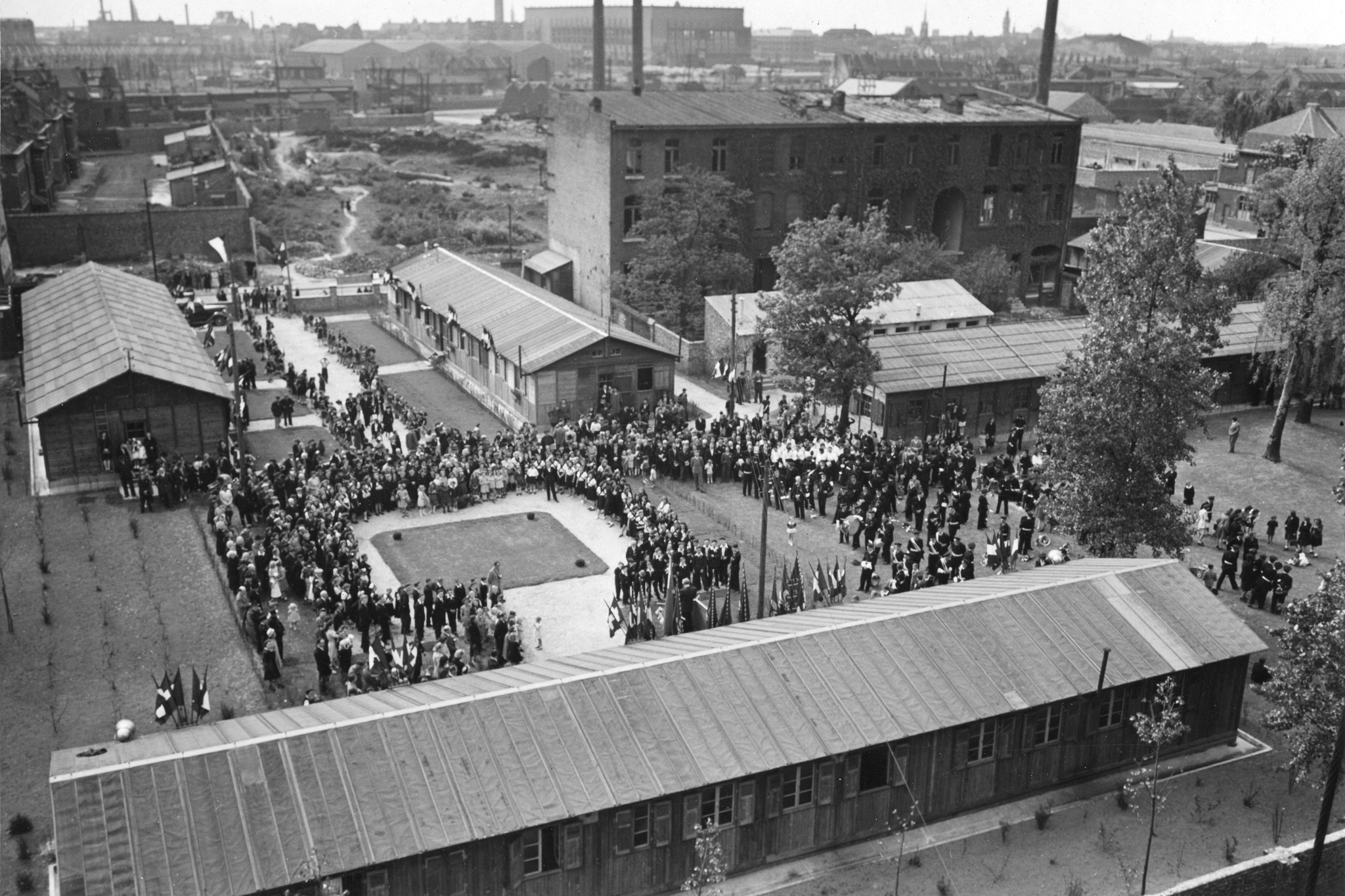 Blick von oben auf  Saint-Lô, die Gebäude das Sozialzentrum des SAH und zahlreiche Personen, vermutlich während des Eröffnungsfestes des Sozialzentrums