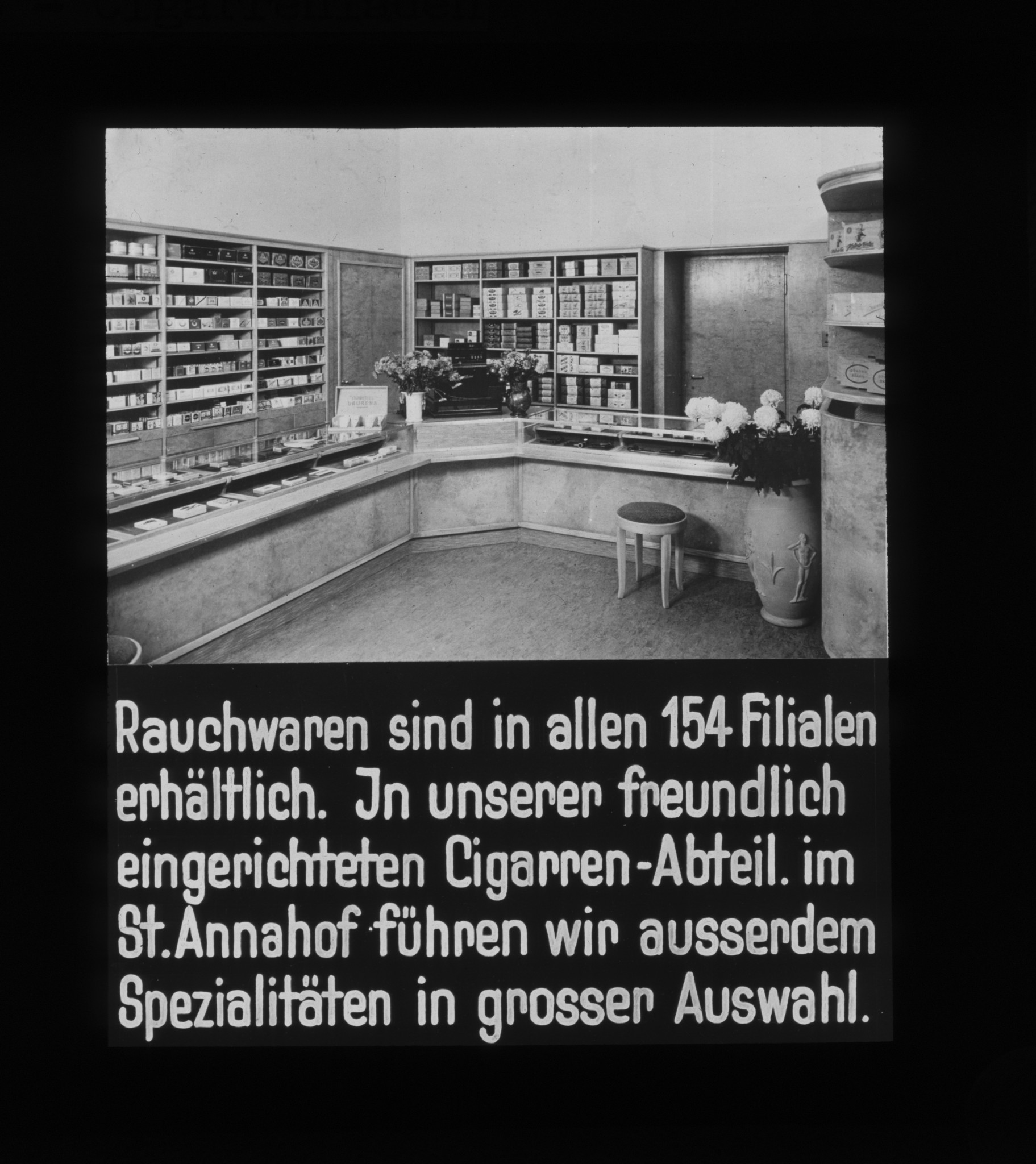 Dia: Zigarren-Abteilung im St. Annahof: "Rauchwaren sind in allen 154 Filialen erhältlich. In unserer freundlich eingerichteten Cigarren-Abteil. im St. Annahof führen wir ausserdem Spezialitäten in grosser Auswahl."