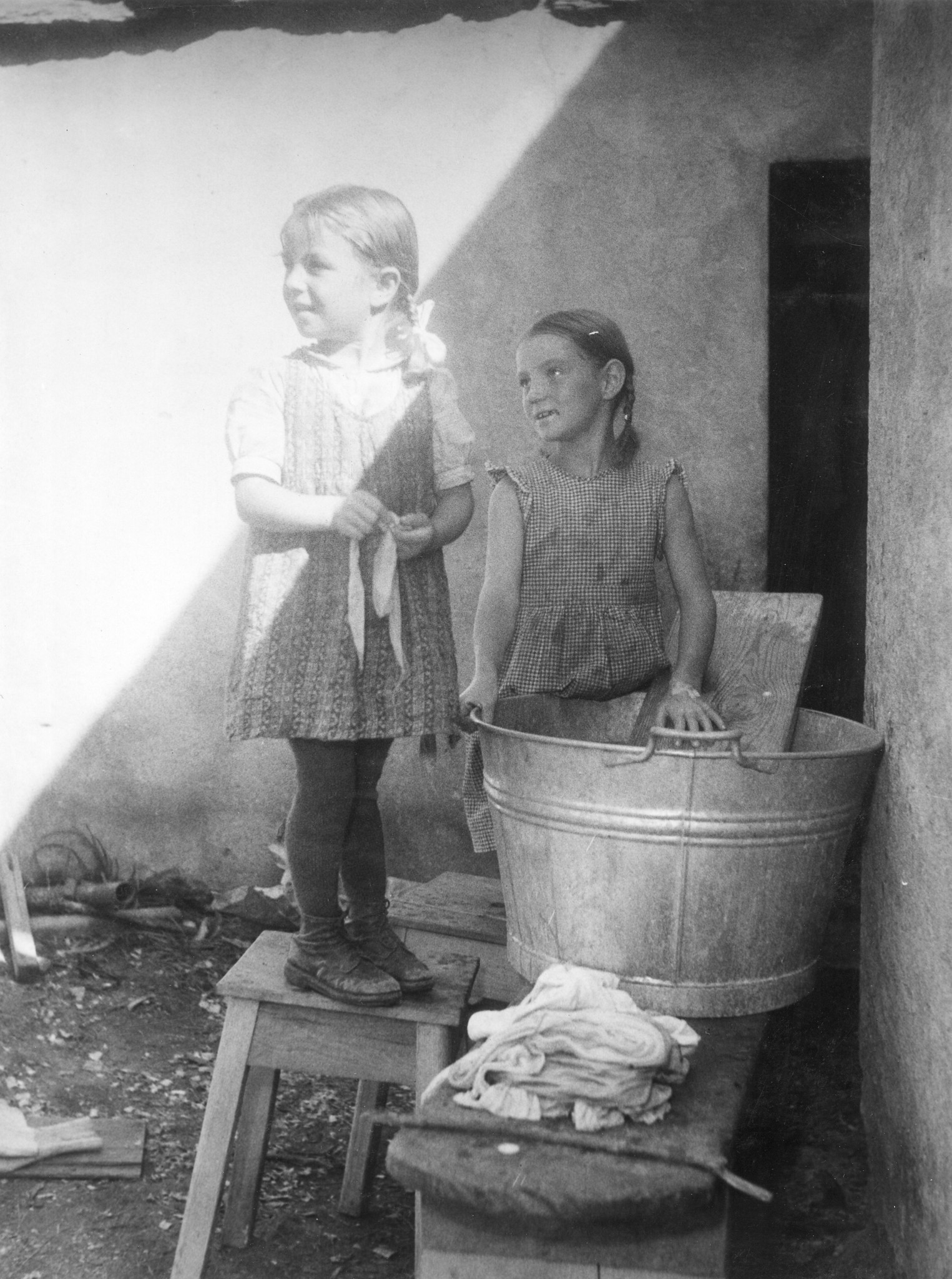 "Die beiden Mädchen waschen vor dem Haus. Es ist ihnen leider kein Vergnügen, sondern eine Pflicht."