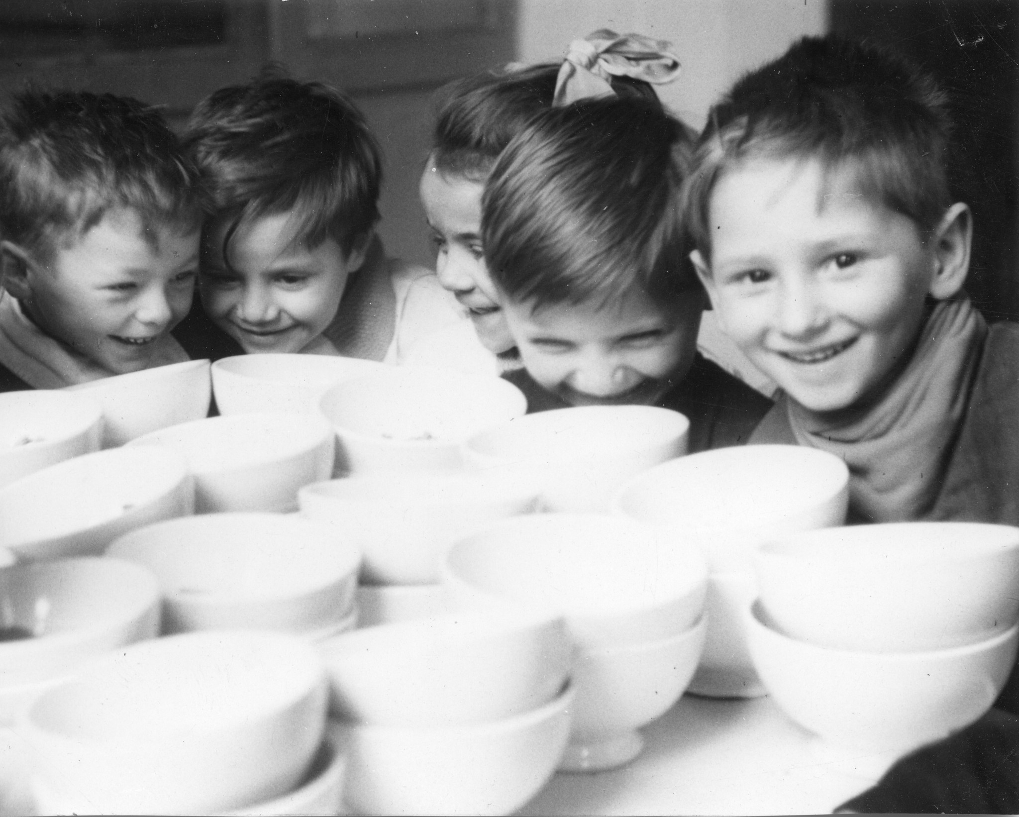 Kinder sitzen lachend vor weissen Schälchen
