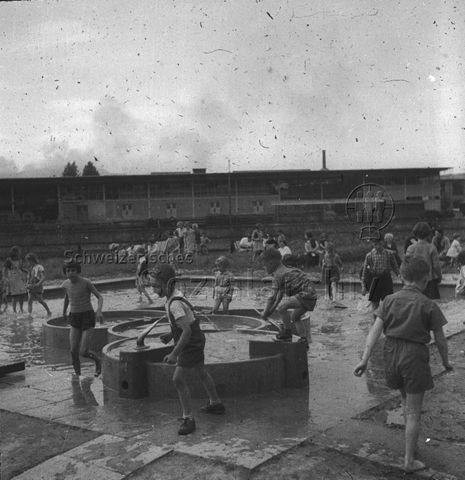 "Freizeitanlagen, Gemeinschaftszentren: FZA Wipkingen, Zürich" - Kinder auf einer Spielwiese mit Brunnen, Sandkasten und Wasserbecken; um 1960