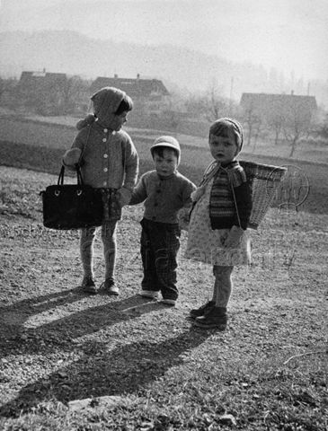 "Bergkinder" - Drei Kinder stehen draussen und halten sich an den Händen; um 1965