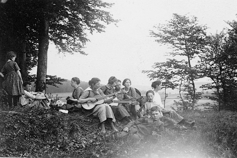 Ausflug der Wandervogel-Ortsgruppe Lichtensteig-Toggenburg - Kleingruppe von Wandervögeln sitzen auf der Wiese: Drei Mädchen spielen