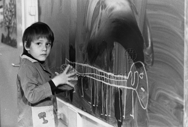 "Kindergarten" - Junge beim Zeichnen an der Wandtafel; um 1980