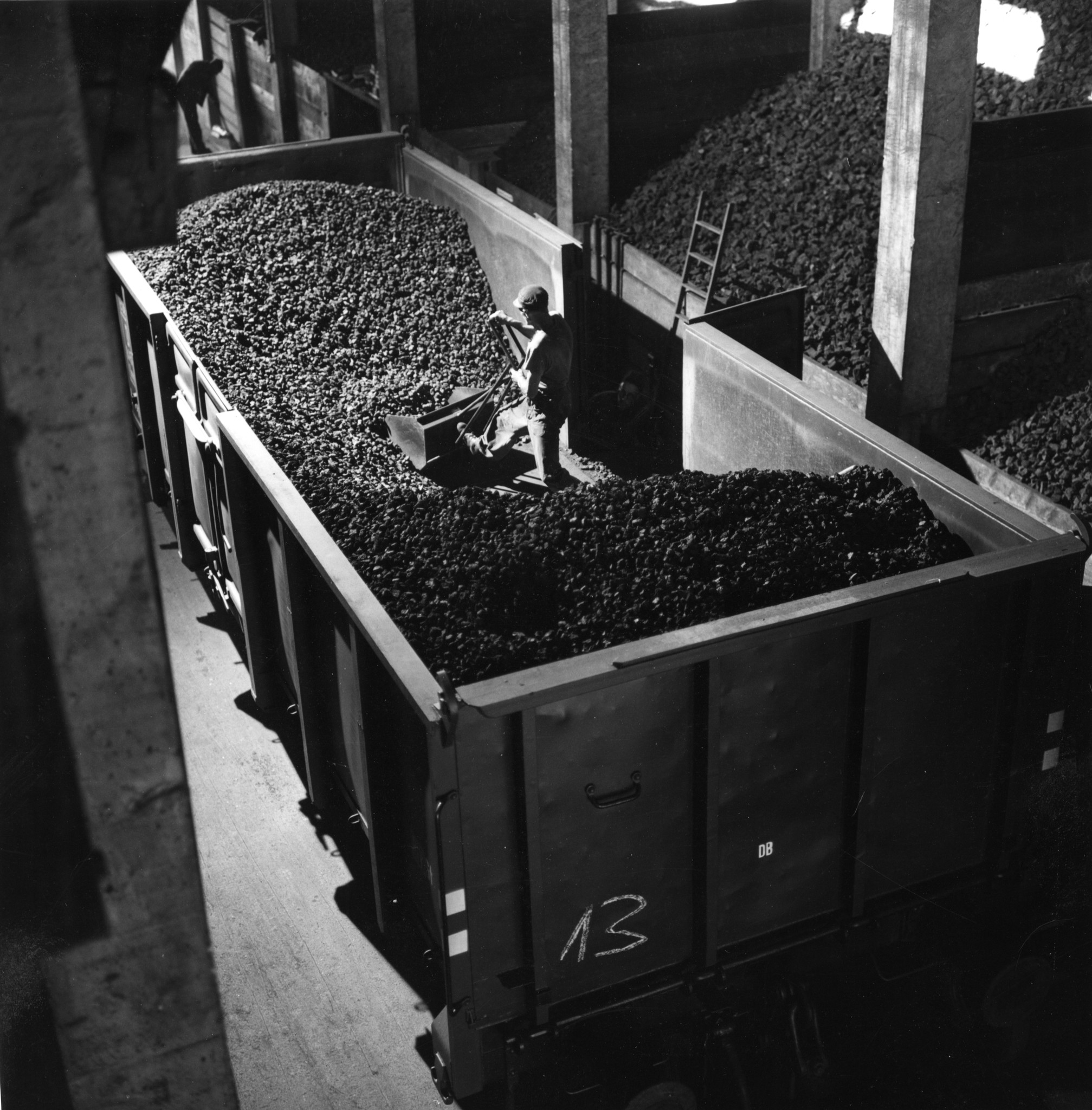 Mann beim Schaufeln von Kohle mit einer grossen Schaufel in einem Eisenbahnwaggon