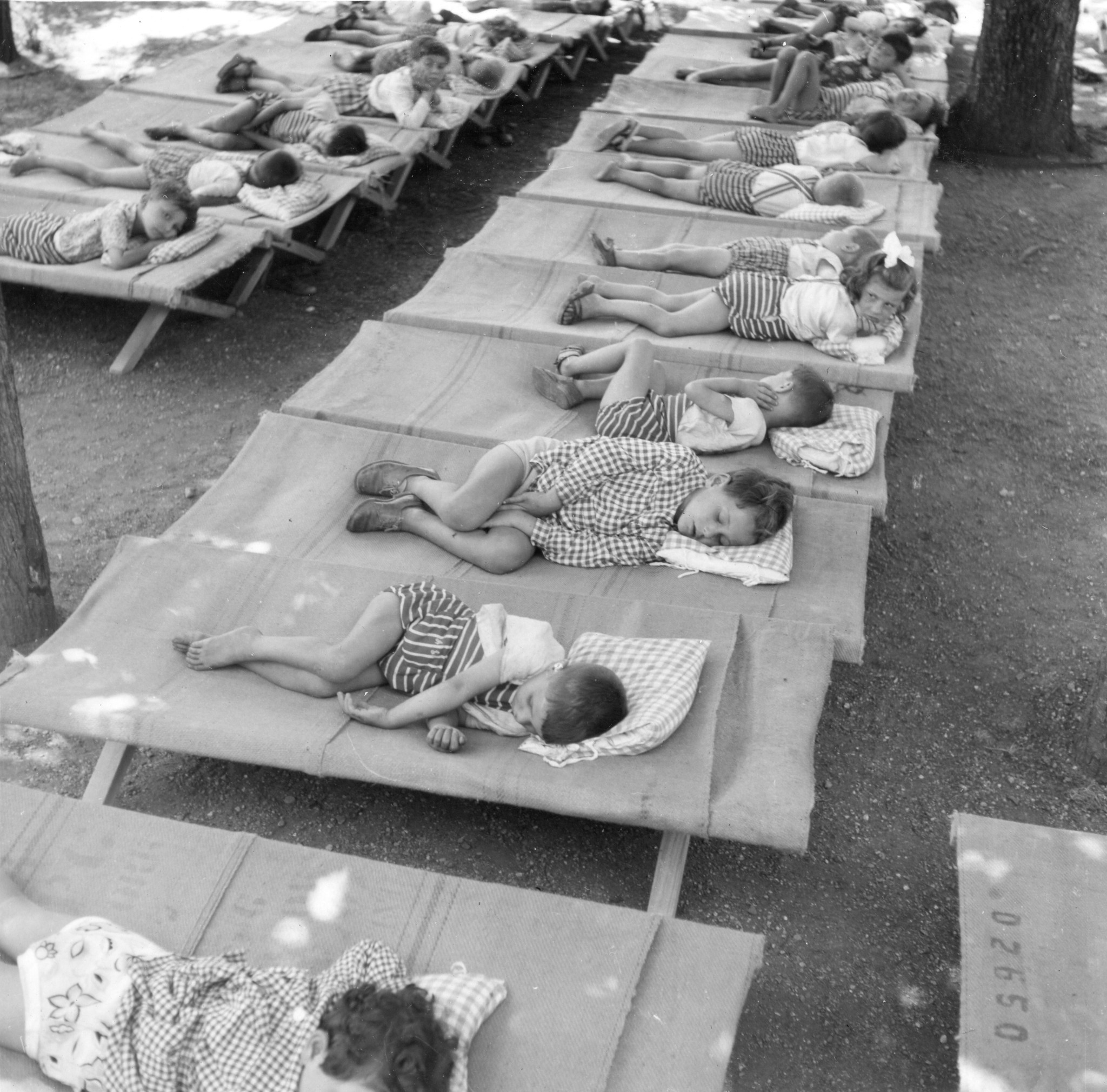 "Milano 1947. Asilo Italo-svizzero"; Kinder liegen im Garten auf Matten und machen Mittagsschlaf
