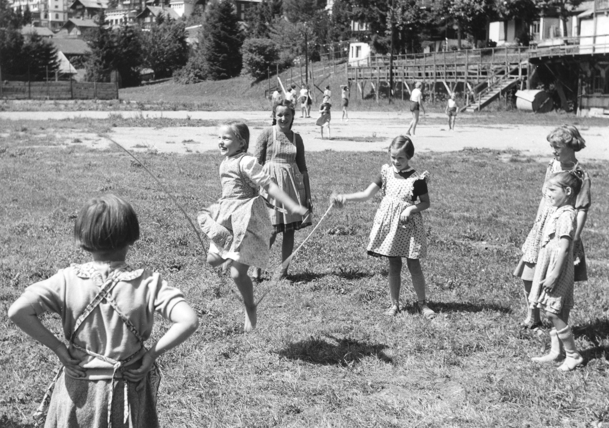 Sechs Mädchen spielen auf einer Wiese mit dem Springseil