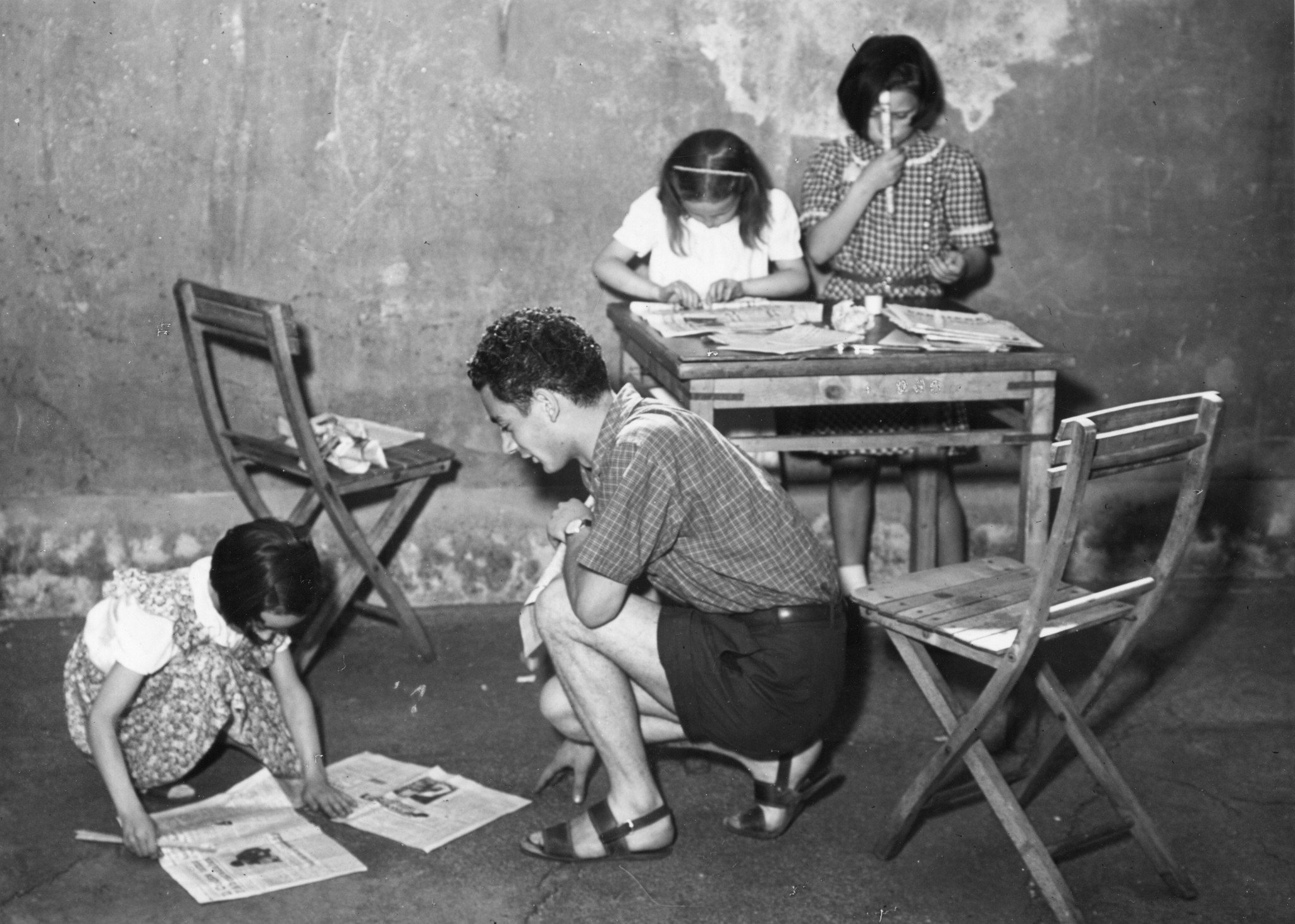 "Moniteurkurs in Mailand unterstützt von Schweizer Europahilfe und SAH 1949", ein Moniteur hilft drei Mädchen beim Basteln