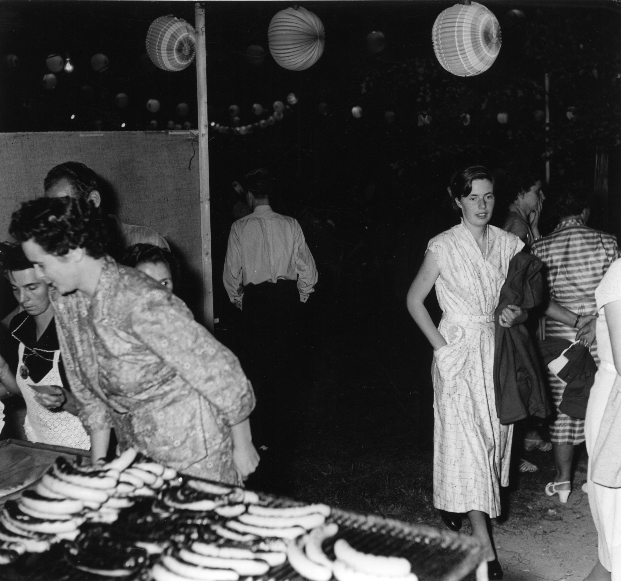 Frauen stehen bei einem Grill mit Würsten, Jubiläum 75 Jahre Lebensmittelverein Zürich 1953