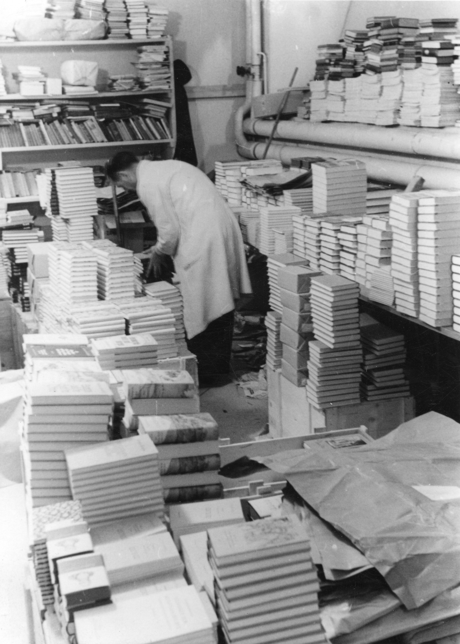 Ein Helfer arbeitet im mit Büchern vollgestellten Raum