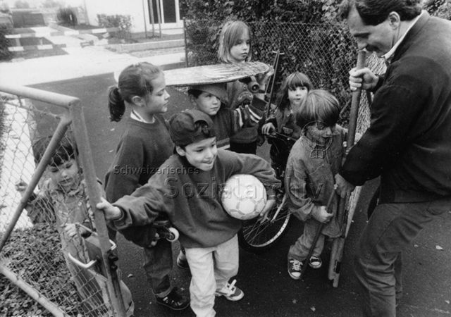 "'Ouvrir ensemble de nouveaux espaces' - Promotion du jeu et de l'espace vital" - Kinder und ein Mann beim Öffnen der Tore zum Spielplatz; 1996