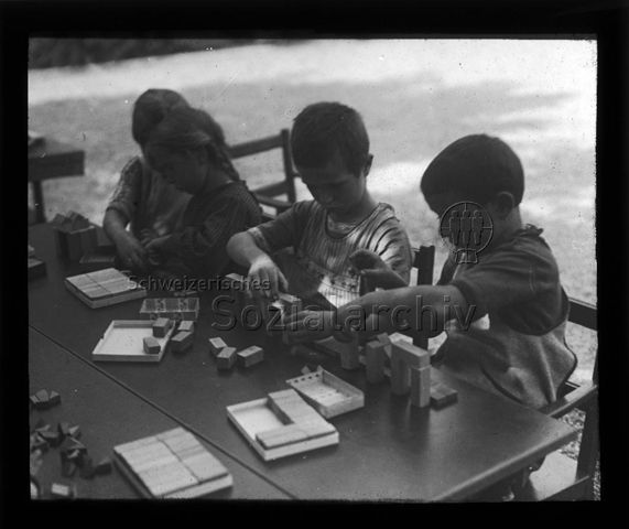 Diaserie zum Thema Kindergarten / Schulkind; Kinder sitzen an einem Tisch und spielen mit Holzklötzen; um 1930