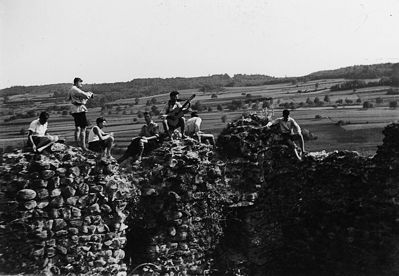 Wandervögel sitzen auf der Burgruine Hälfenberg (vermutlich) - Ein Wandervogel Gitarre spielend (Juni 1932)