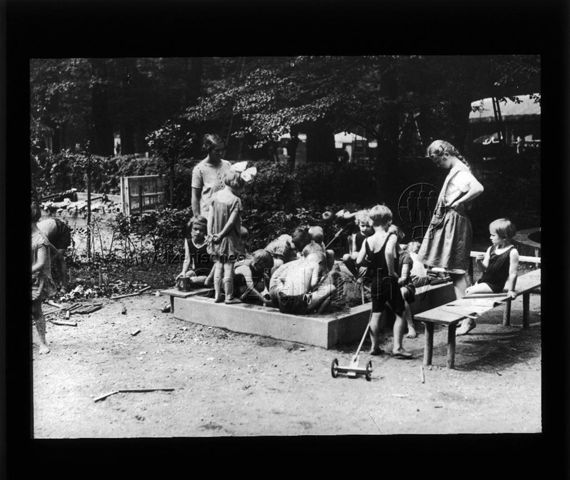 Diaserie zum Thema Tuberkulose im Kindesalter; Auf dem Spielplatz; Kinder spielen mit zwei Aufseherinnen in einem Sandkasten; Deutsches Hygiene-Museum; um 1930