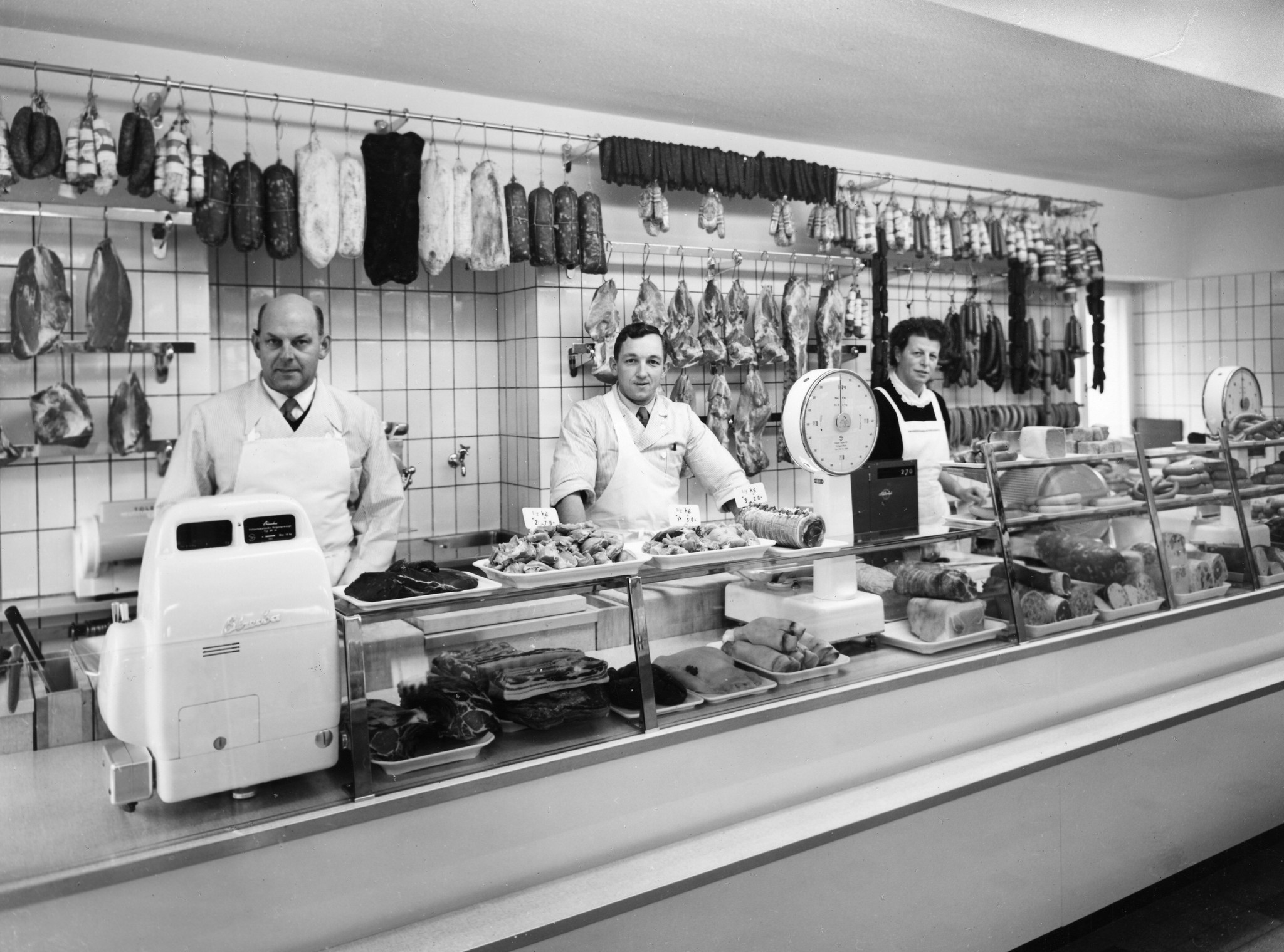 Metzger und Charctuerieverkäuferin hinter der Theke der Metzgerei einer Coop-Filiale, um 1955