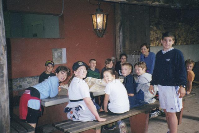 Bosco della Bella, Feriendorf für kinderreiche Familien - Kinder, Jugendliche und eine Frau versammelt am Tisch; 2000
