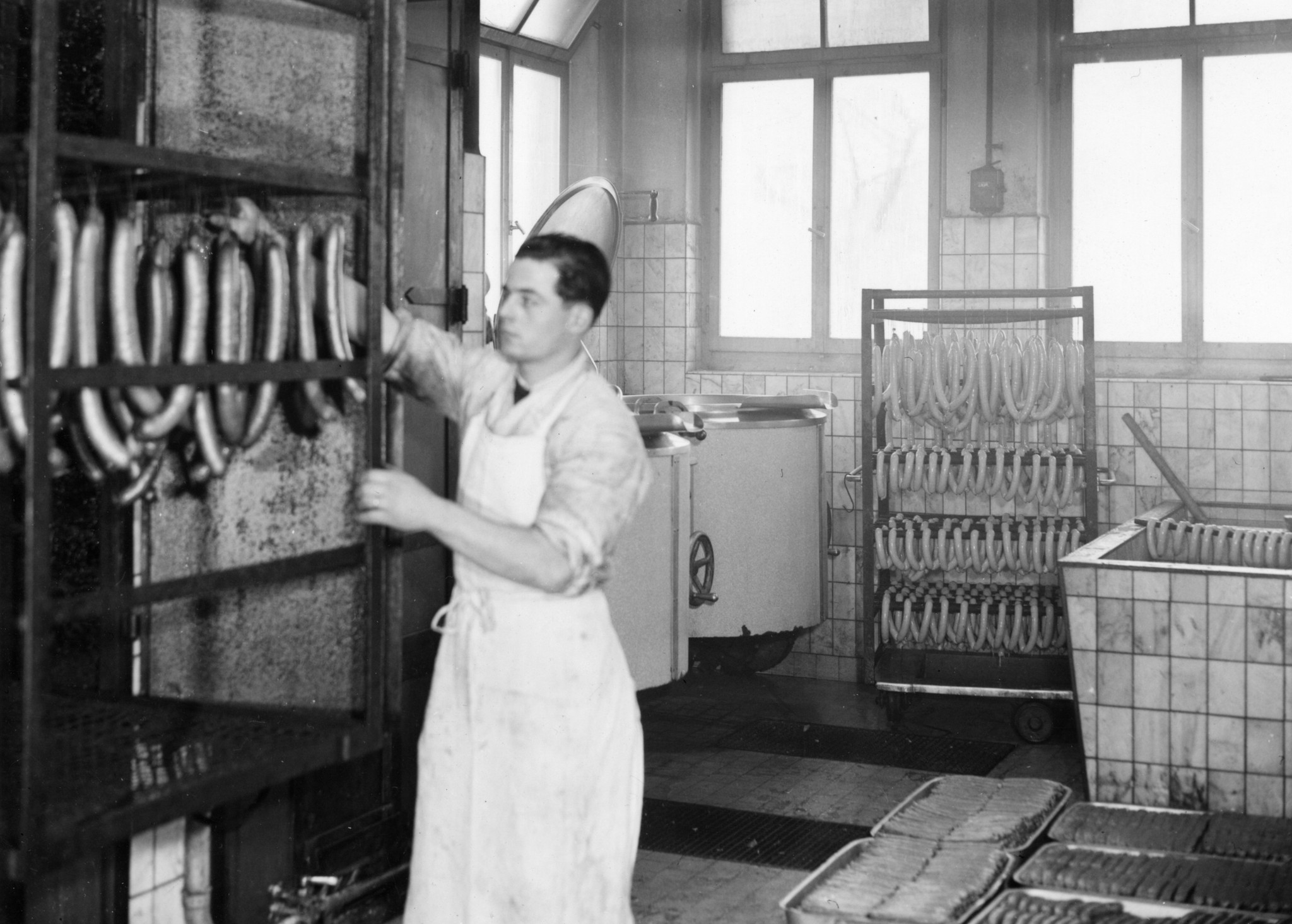 Mann beim Aufhängen von Würsten in einer Produktionsküche