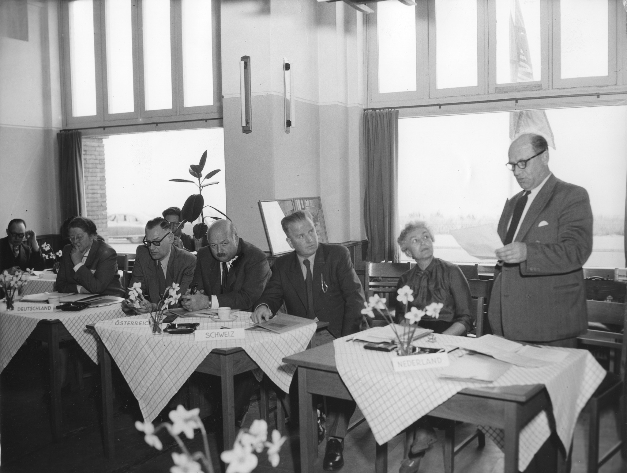 Zusammenkunft der Mitglieder des Internationalen Arbeiterhilfswerk, die Parteien sitzen in einem Kreis; ein Mann hält eine Rede