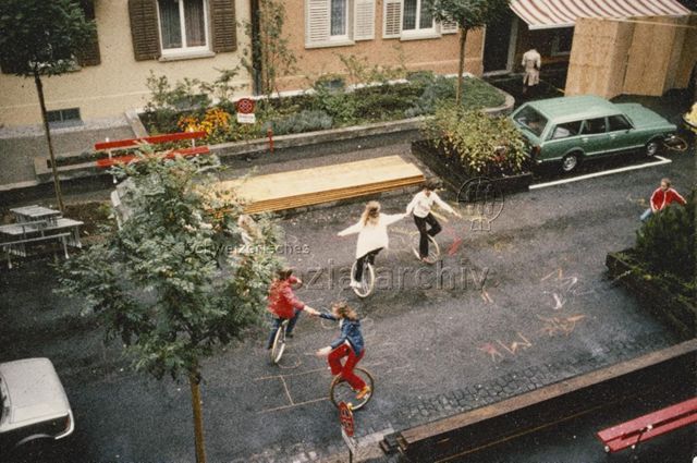 "Wohnstrassen" - Vier Kinder beim Einradfahren auf einer Strasse im Wohngebiet; um 1975