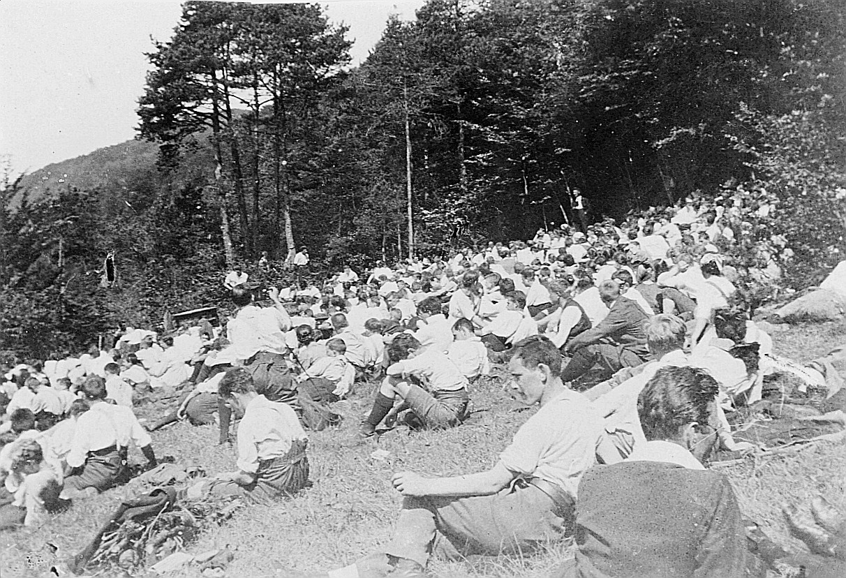 Versammelte Wandervögel sitzen auf der Wiese an der Wandervogel-Landsgemeinde in Biberstein - Ein Wandervogel anhand eines Stativs m
